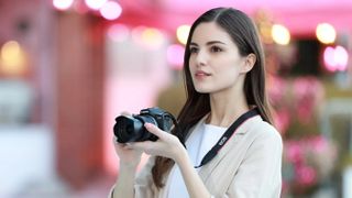 Woman holding a Canon EOS R100 camera