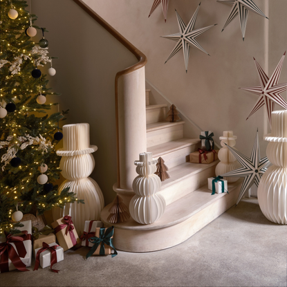 Habitat paper snowman next to a christmas tree in a hallway. Paper stars are on the wall and there are loads of wrapped presents.