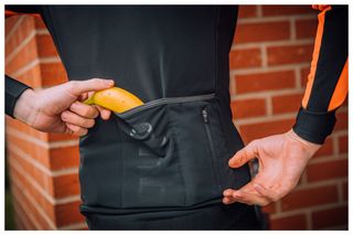 A cyclist reaches for a banana from their back pocket