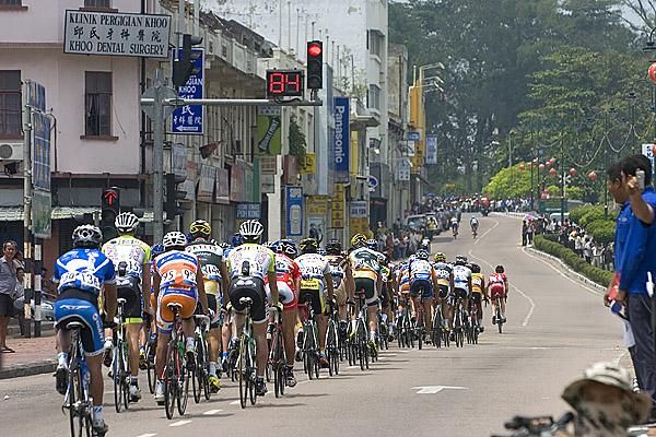 The peloton pass through a Malaysian town heading towards the finish in Parit Sulong.