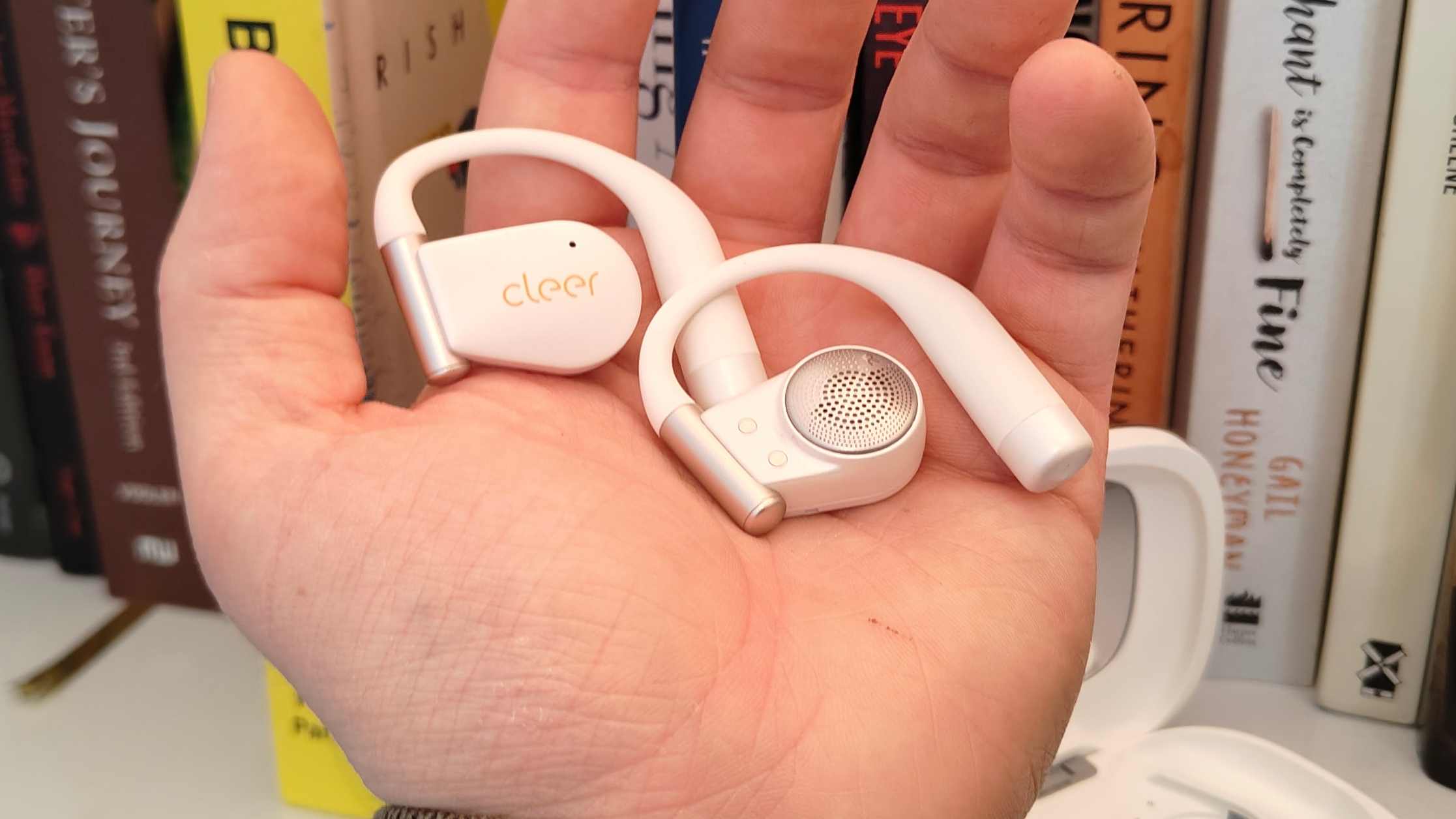The Cleer Arc 5 buds in a man's hand.