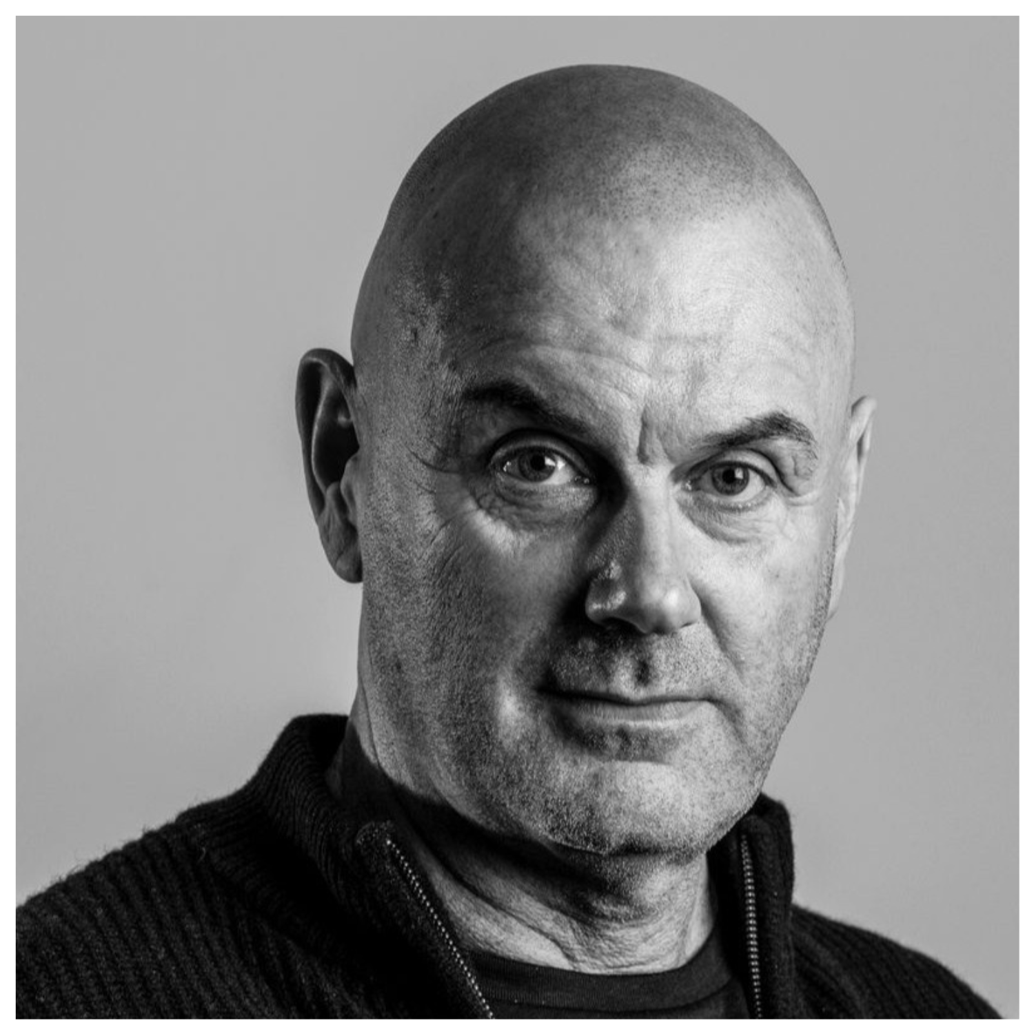 A black and white photo of a man in a zip-up sweater