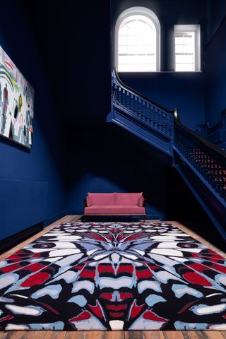 Alexander McQueen's Painted Lady rug in a dark painted hallway