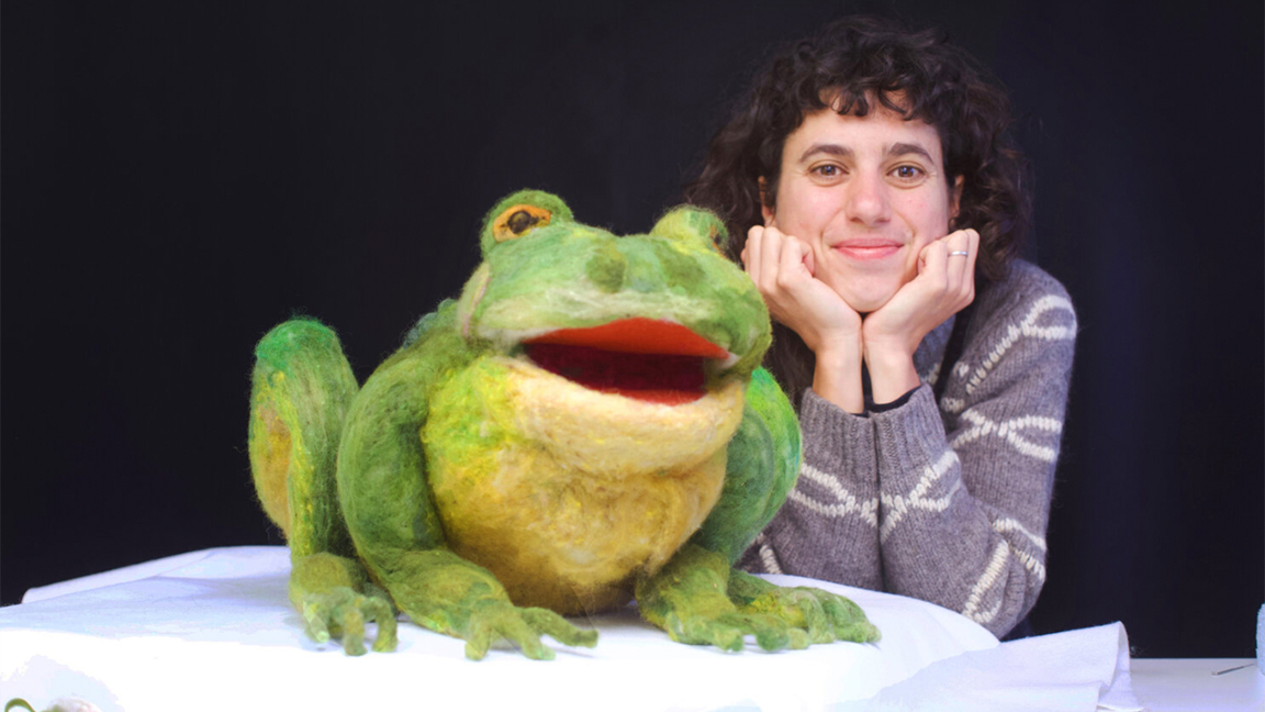International Women's Day: a women sits next to a giant frog made from felt