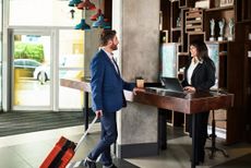 Businessman with suitcase arriving at hotel reception