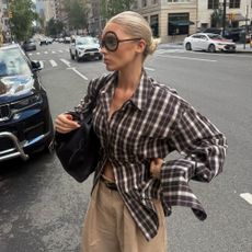 An image of Elsa Hosk wearing beige trousers with a checked shirt whilst in New York. 