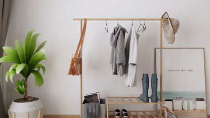 A clothing rail with clothes hanging from it, and a bag slung on the end