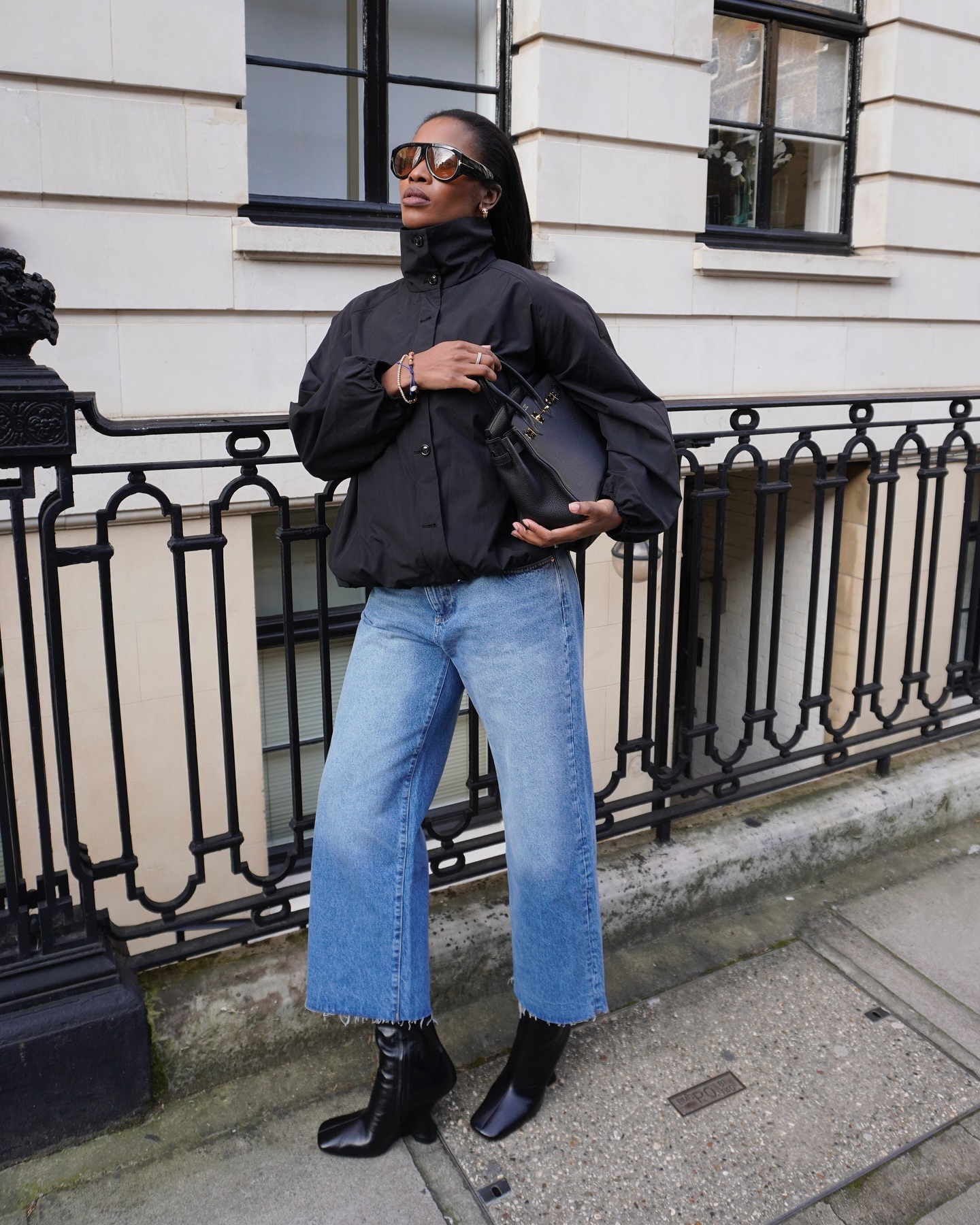 Influencer Marilyn wears a funnel-neck jacket with raw hem light-wash jeans and black leather boots.