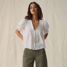 Woman wears white blouse, olive jeans