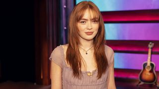 Sadie Sink stares directly at the camera in a pink tee while readying for The Kelly Clarkson show 2026.