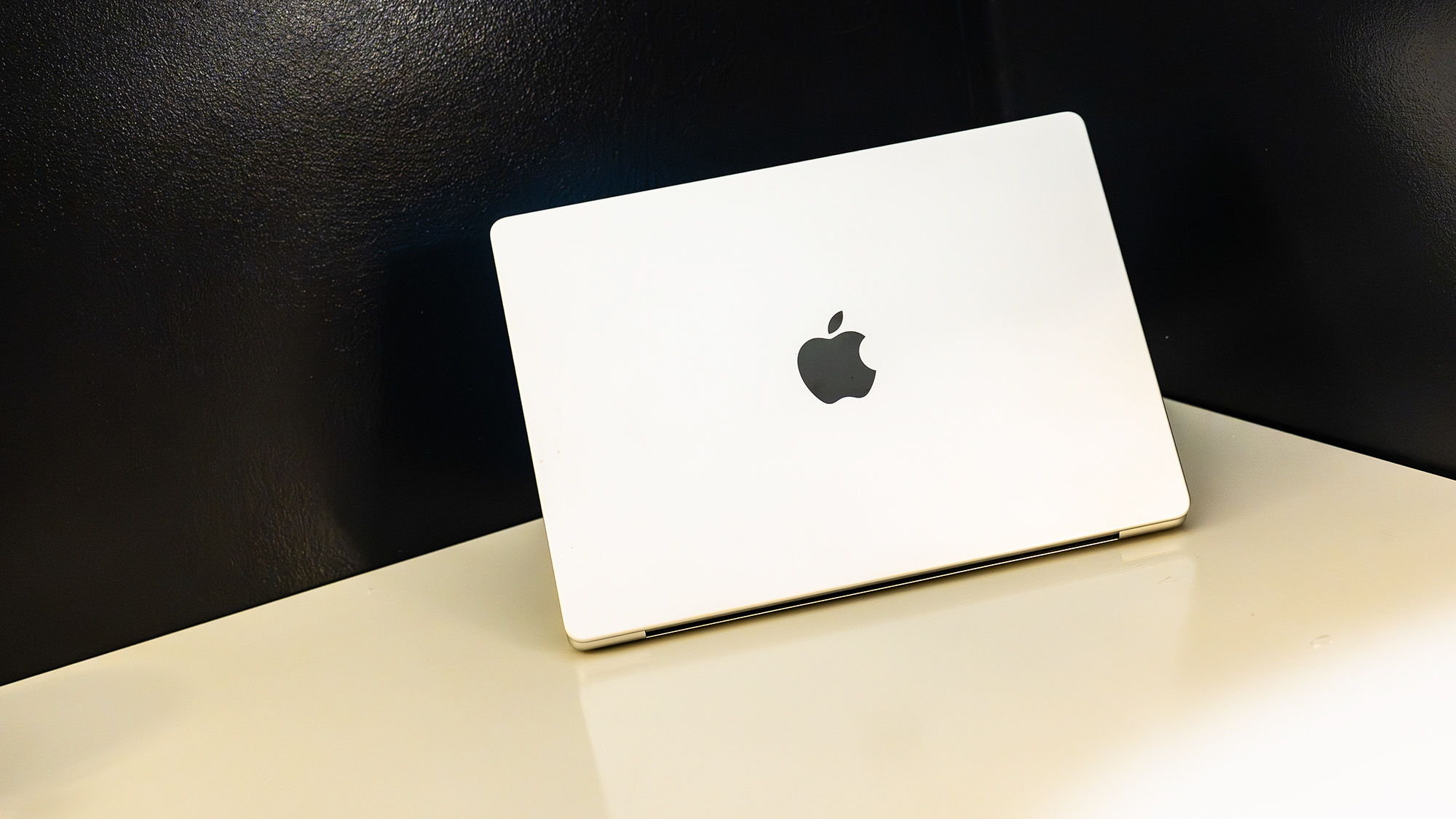 Apple MacBook Pro 14 (M5 Max) on a white table in front of a black wall
