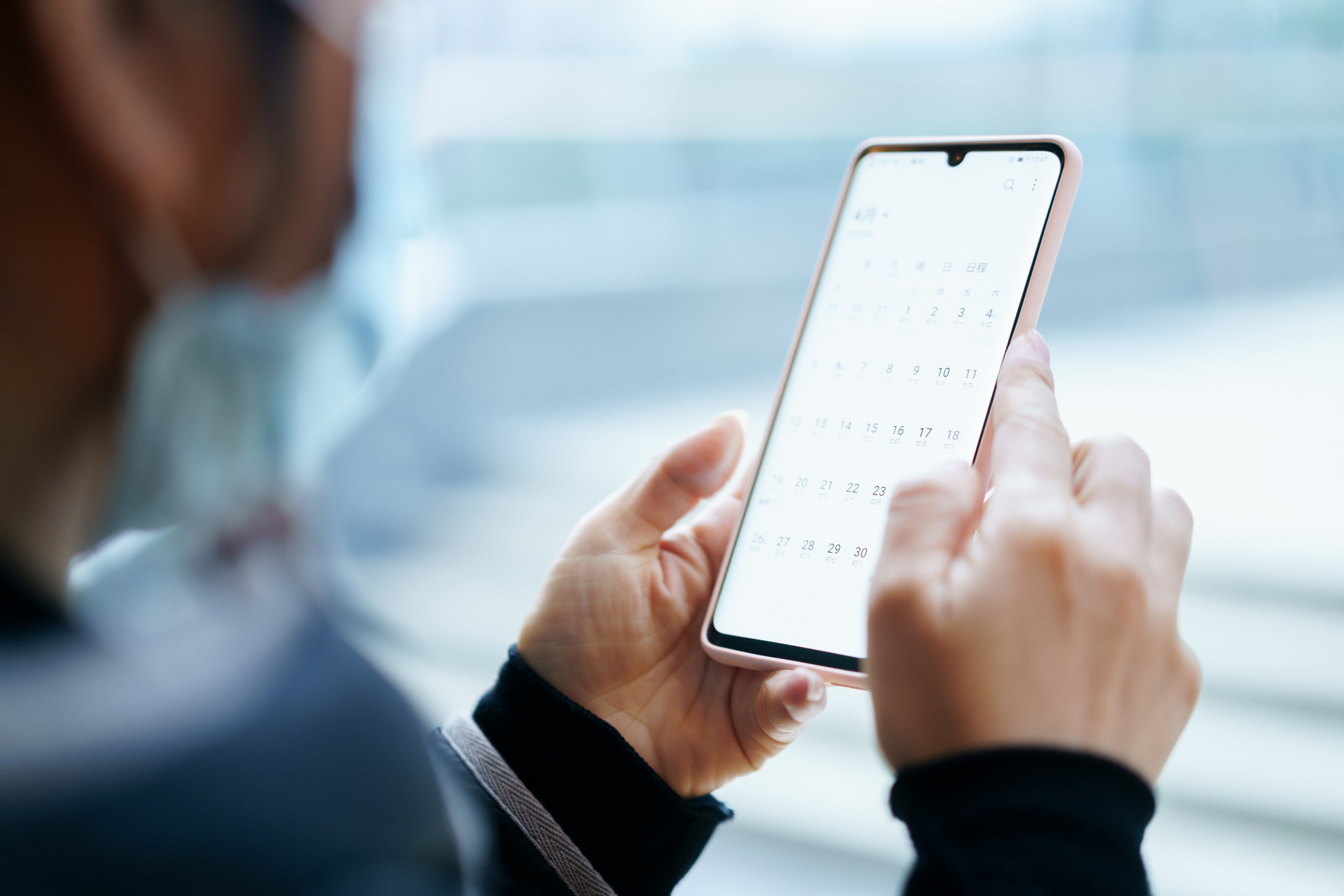 A person holding their phone while using a calendar app.