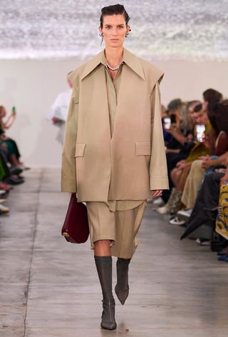 photo of a model wearing a tan outfit with gray t-strap sandals with sheer socks on Jil Sander's spring runway show