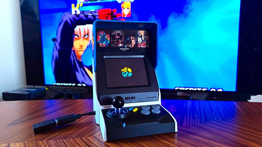 Neo Geo Mini on woodgrain table with gameplay in backdrop on TV.