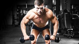 Man performing an upper body workout using two dumbbells front facing camera