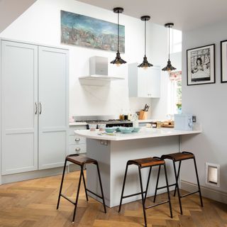 modern kitchen with breakfast bar and stools with three pendant lights