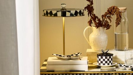 Mackenzie-Childs Courtly Check portable lamp styled alongside tableware from the collection, including a lidded ceramic vessel and various trinket trays.