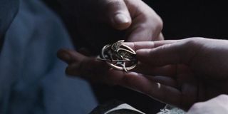Prim hands Katniss the Mockingjay pin