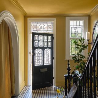 A yellow hallway with an arched doorway painted in Farrow & Ball's Duster shade