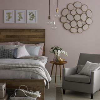 pink wall bedroom with wooden bed and grey chair