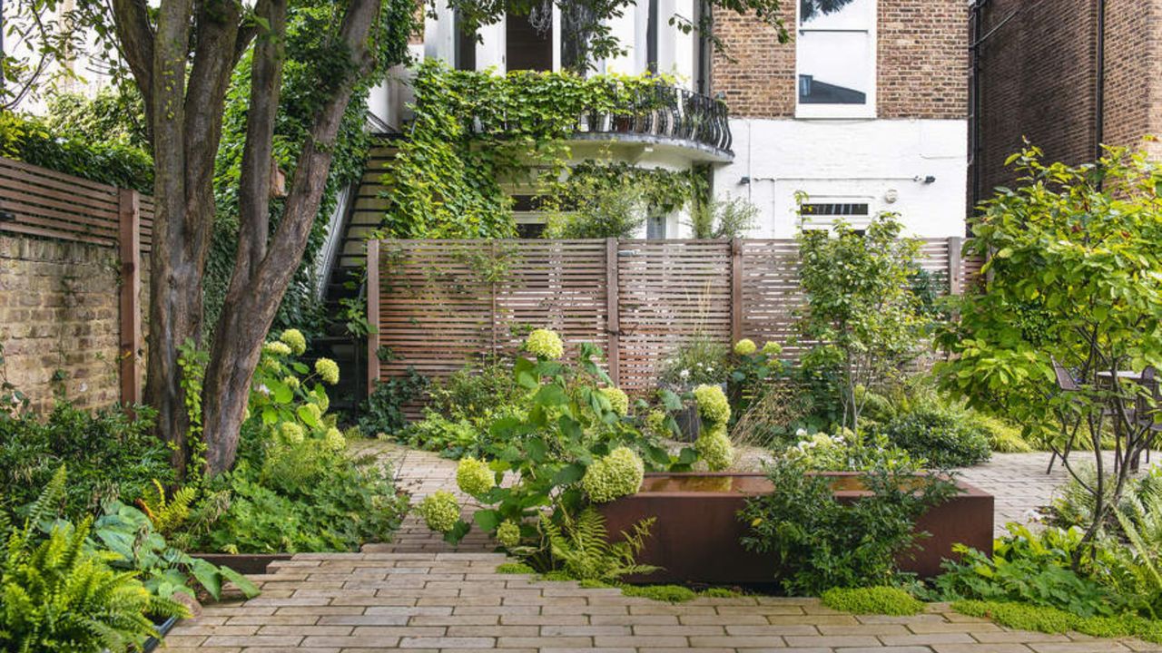 Patio area with hydrangea&#039;s shrubs, water feature with house in the background. Karen Howden and Tom Gandey&#039;s ground floor flat&#039;s garden in North London.