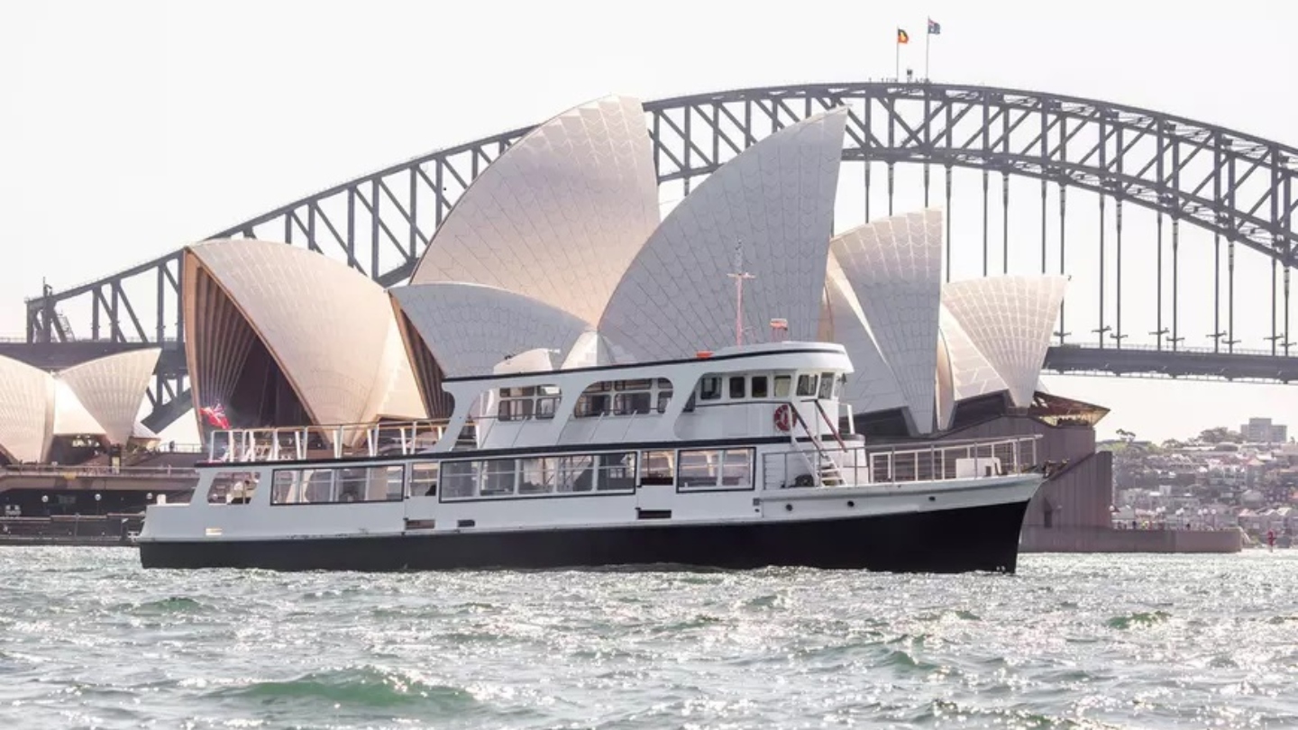 A boat on the harbour in front of the Opera House and Harbour Bridge