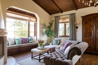 sofa and window seat with pale stone floors wooden ceiling and corner fireplace