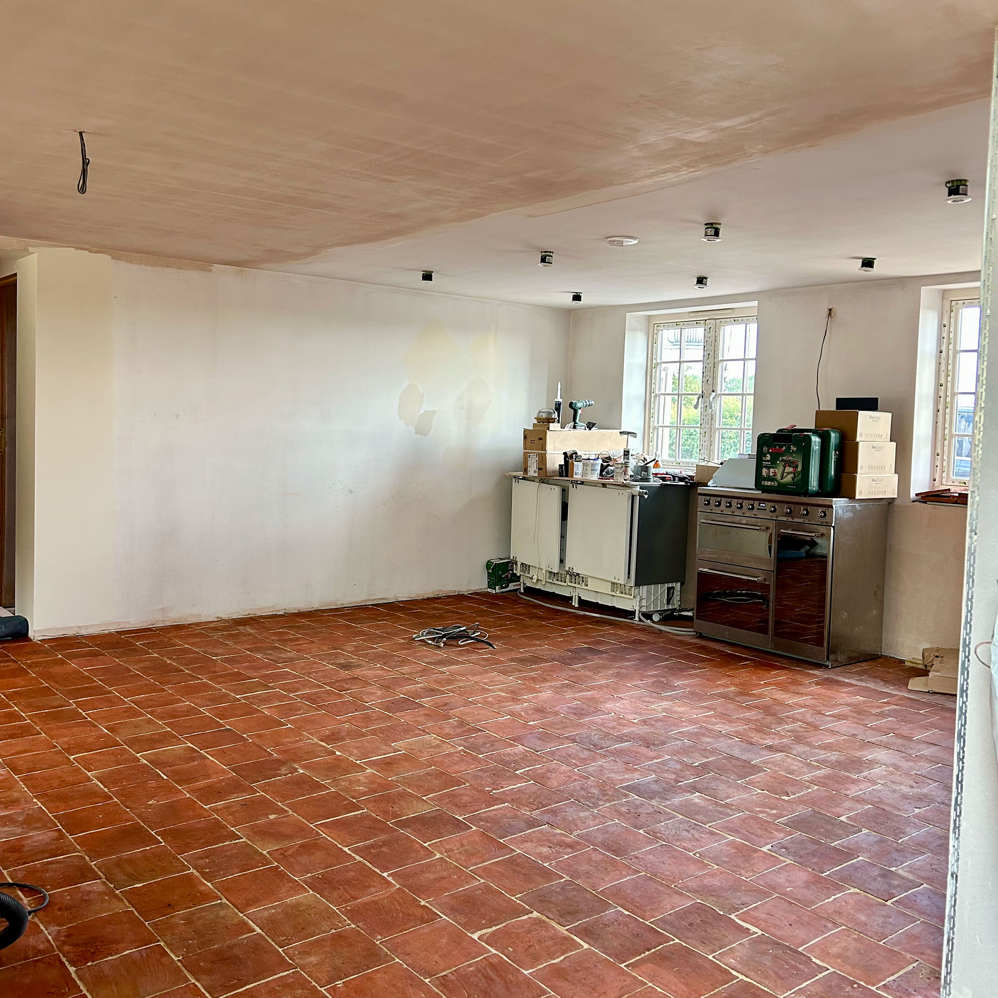 Open plan kitchen area in construction phase with terracotta tiled floors