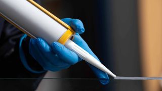 closeup of silicone glue gun being applied to glass