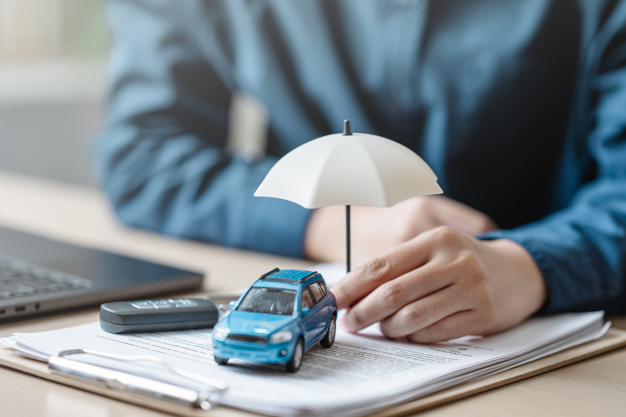 a picture of a car and key fob on top of paperwork covered by an umbrella