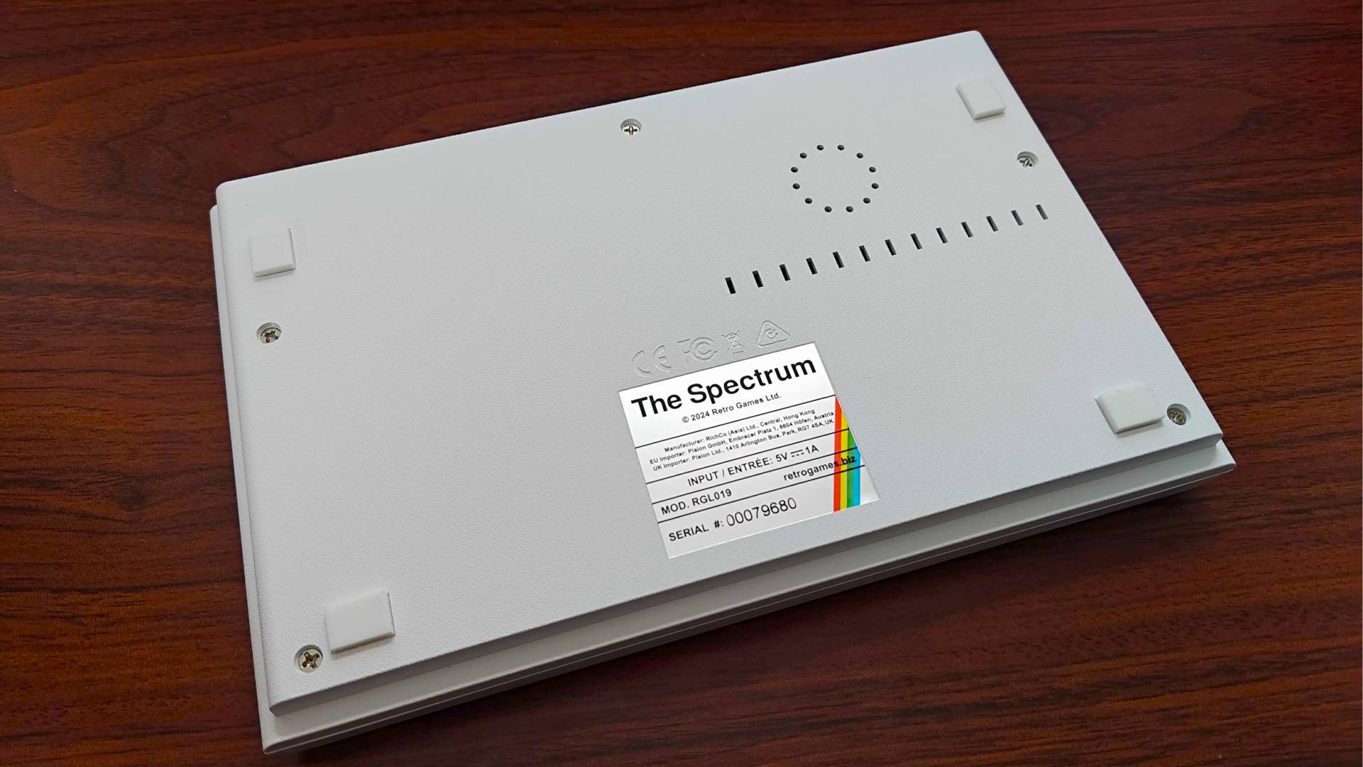 The Spectrum White Edition upsidedown on woodgrain desk.
