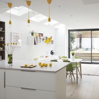 White kitchen with counter, table, chairs and yellow pendant lights