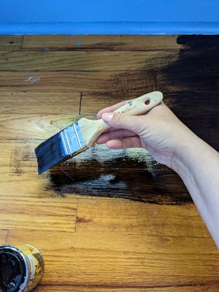 hand painting gel stain on wood floor with paintbrush