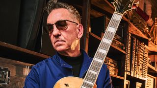 Portrait of Richard Hawley in sunglasses with his vintage Gretsch guitars