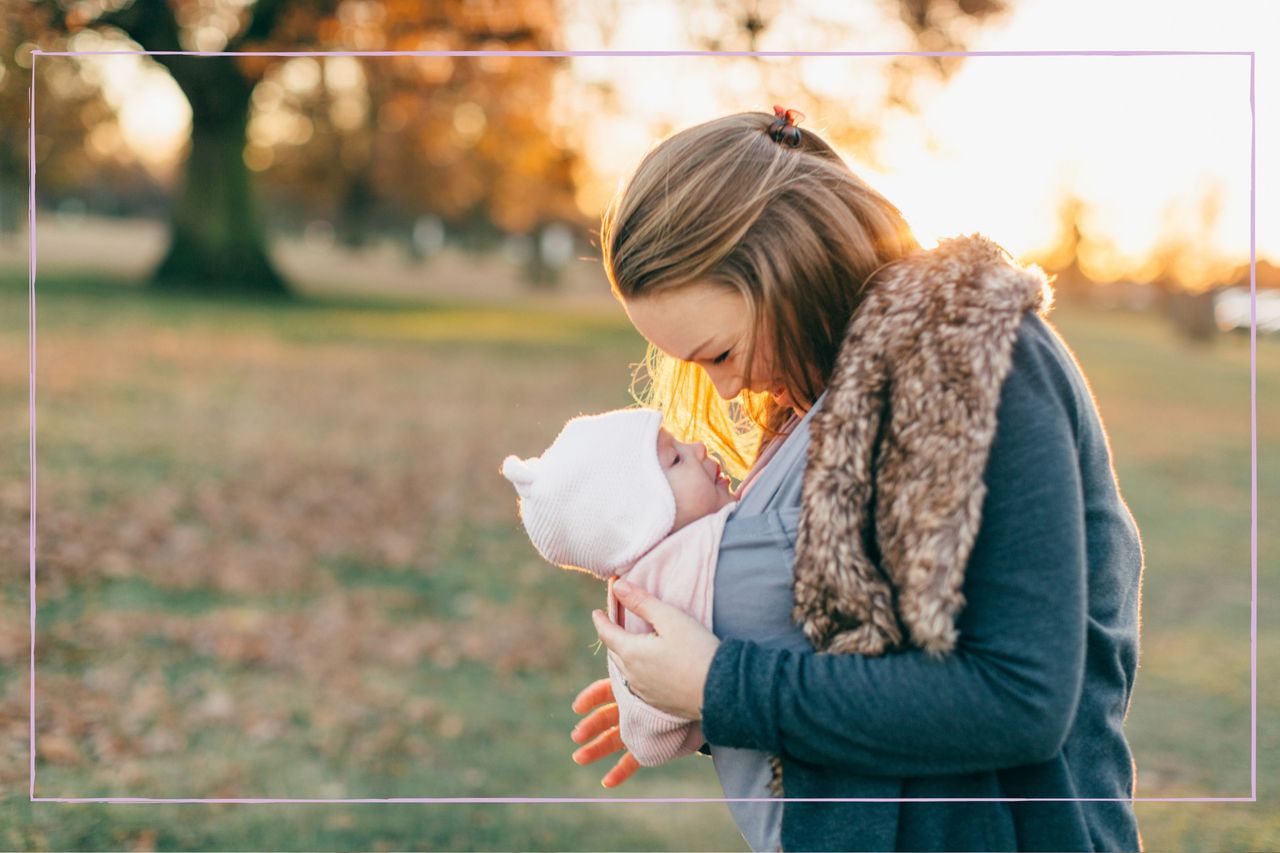 Attachment parenting, as illustrated by a mother carrying her baby in a sling and smiling