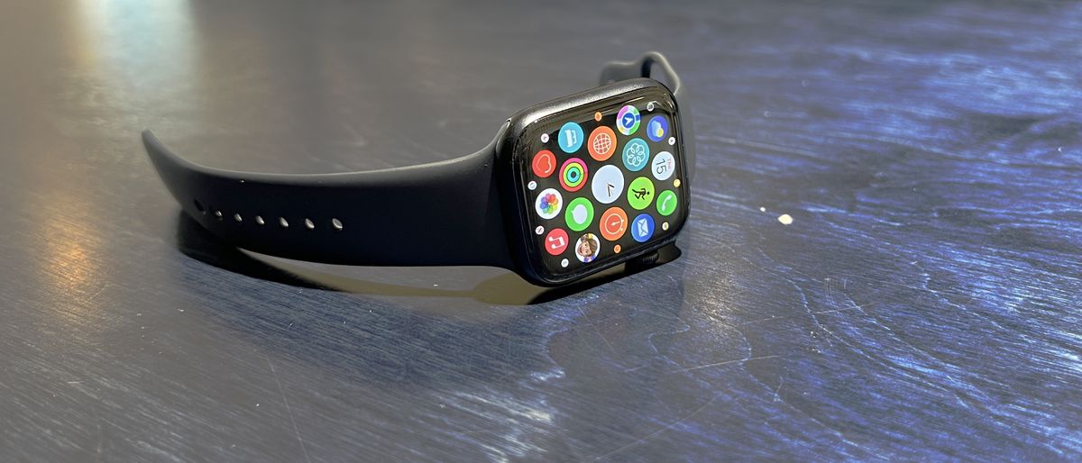 The Apple WAtch 8 on a blue desk and wrist