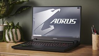 En Gigabyte Aorus 17G står öppnad på ett skrivbord bredvid lite växter.