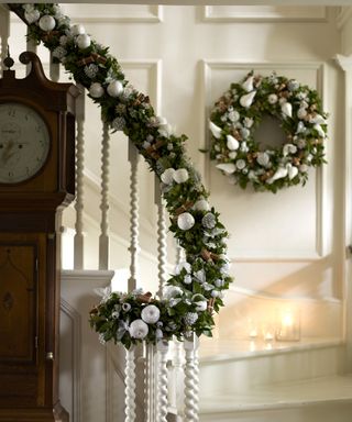 Christmas stair decor ideas with a pine garland with cinnamon sticks and white painted apples and pine cones, with matching wreath