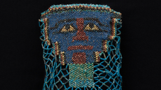 close-up of a beaded funeral shroud depicting a face, mostly with blue beads