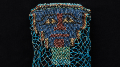 close-up of a beaded funeral shroud depicting a face, mostly with blue beads