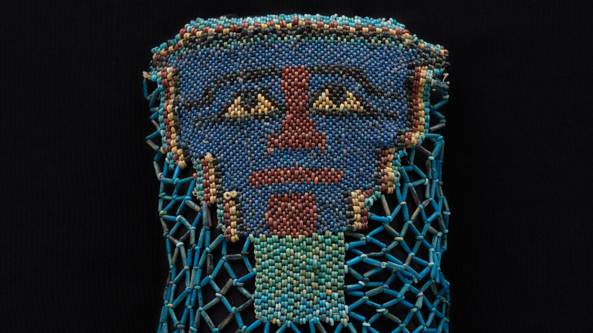 close-up of a beaded funeral shroud depicting a face, mostly with blue beads