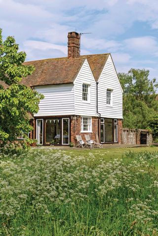 The exterior of a modernised and extended 14th century farmhouse with meadowscaping