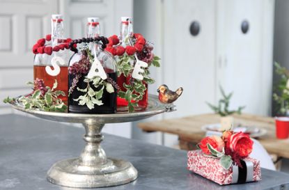 three bottles of home made sloe gin on a cake stand