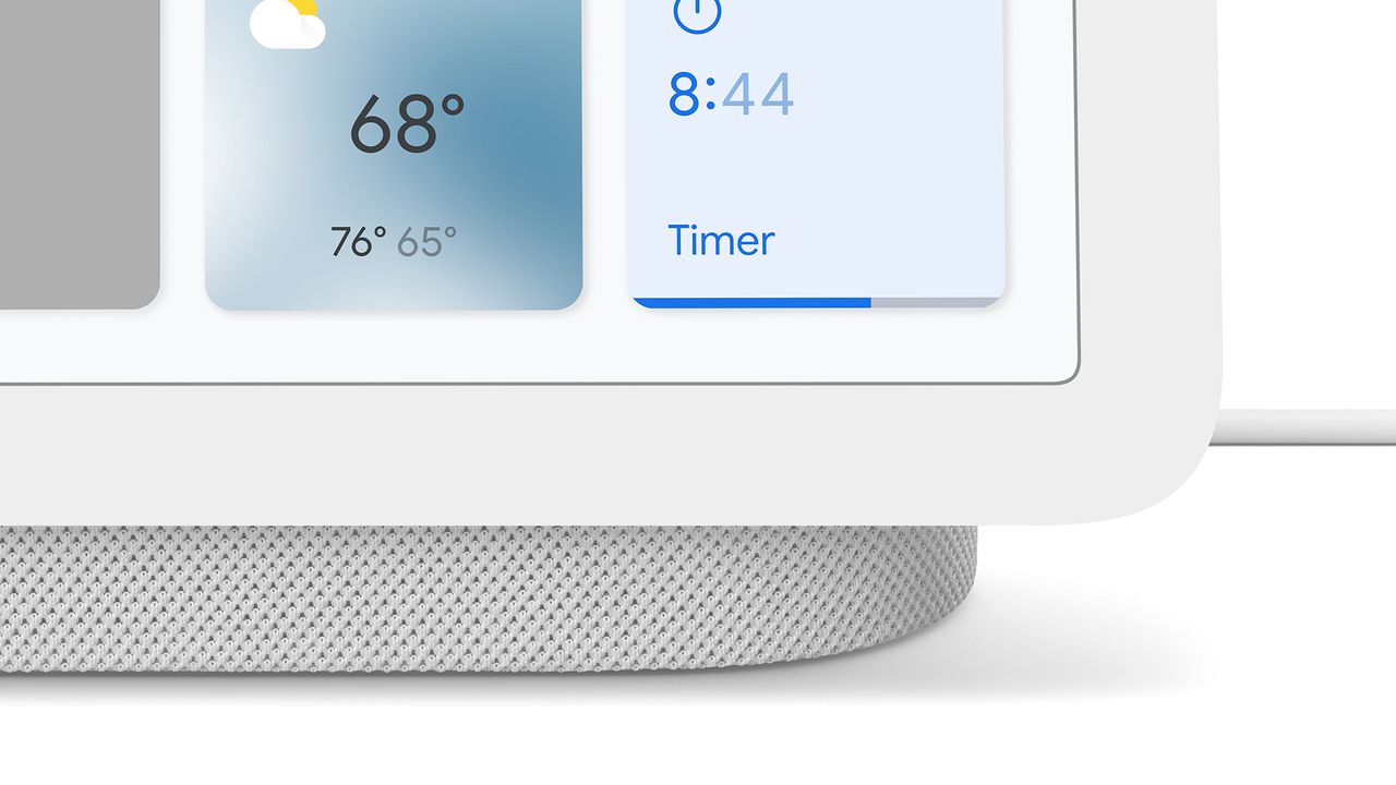 A close-up of the Google Nest Hub (2nd Generation) speaker. It shows the bottom portion of the screen, the grey base and the power cable.