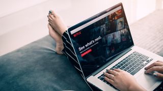 Personne regardant Netflix sur son Mac posé sur les genoux