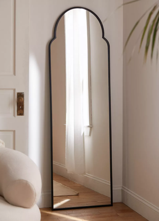 full-length black arch mirror leaning on a wall