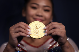 suni lee with an olympic manicure holding a gold medal