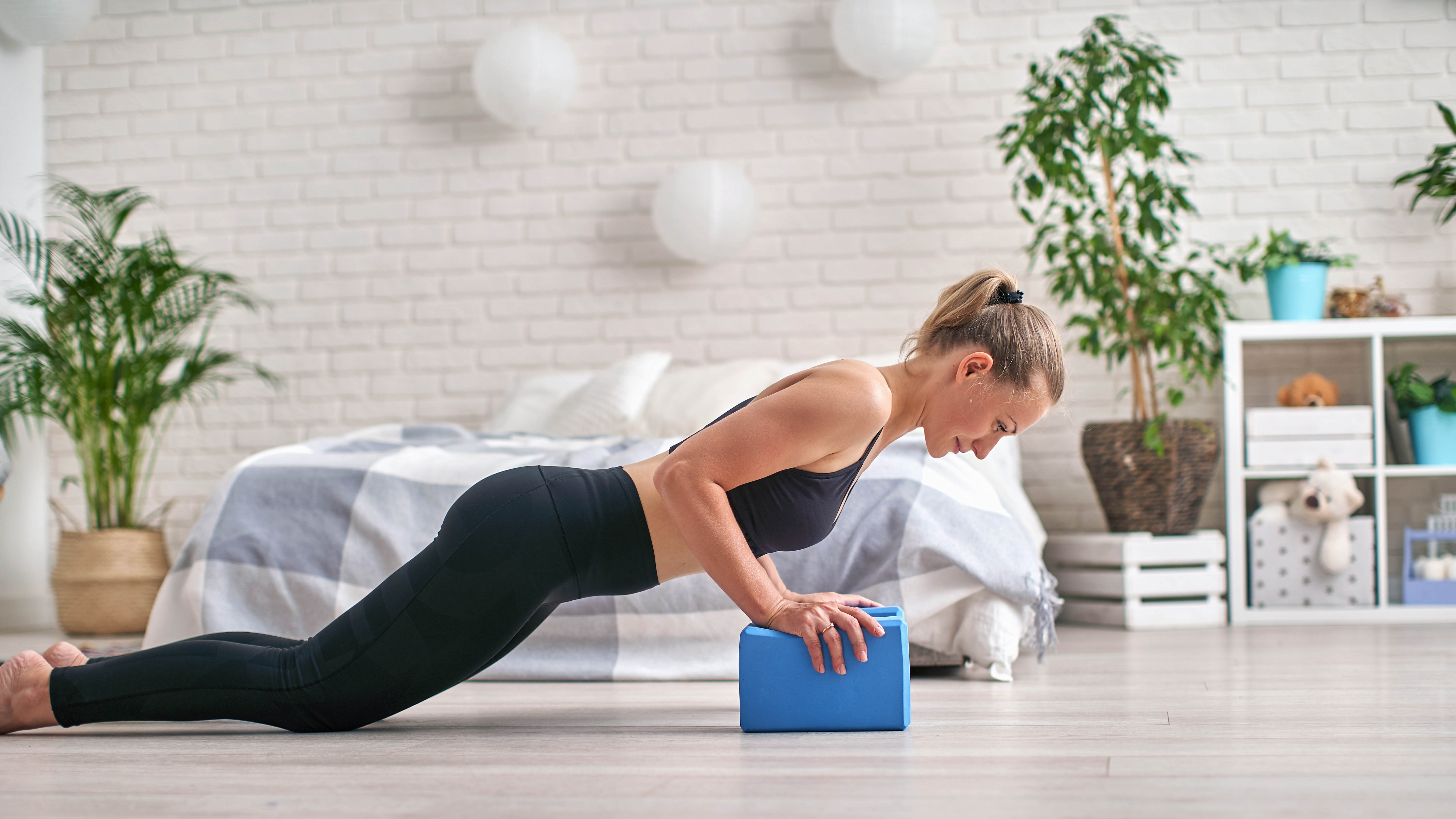 Woman doing yoga in bedroom with yoga blocks