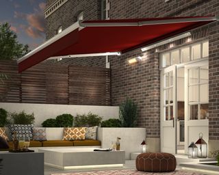 A red garden awning over a patio seating area near a house
