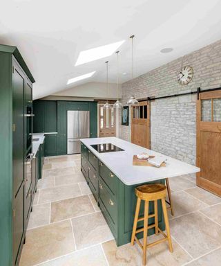 A kitchen with green cabinetry and two wooden barn doors